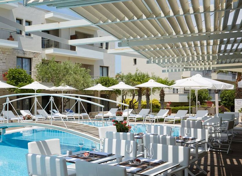 Poolside lounge area at Renaissance Hanioti Resort in Afytos with umbrellas, loungers and a bridge