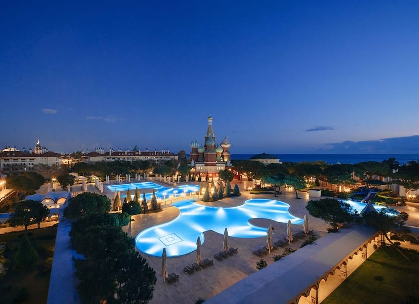 PGS Hotels Kremlin Palace in Antalya with illuminated pool area and sea view at dusk