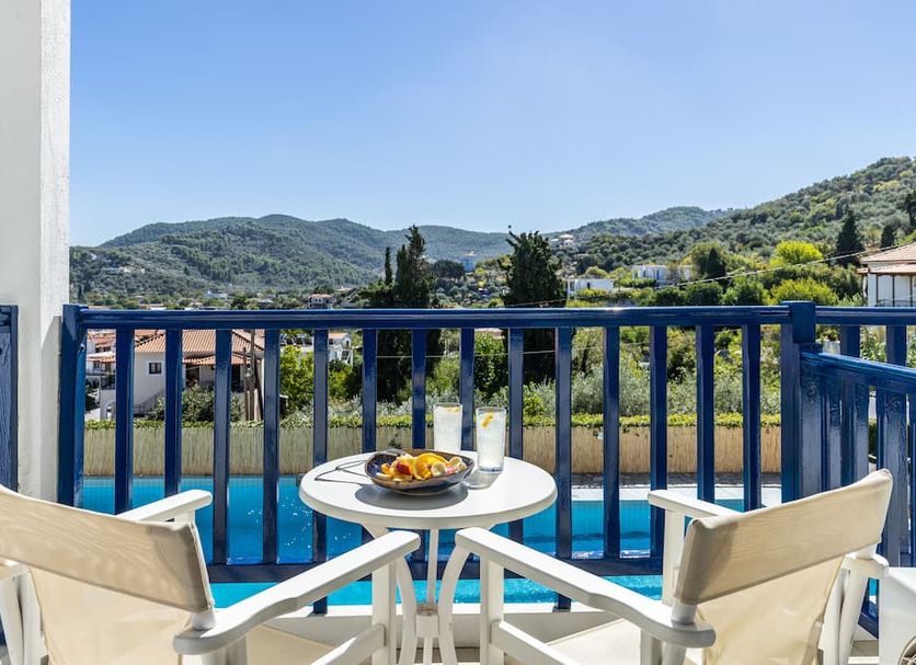 Aperitton in Skopelos balcony with table, chairs, pool view and green mountain backdrop