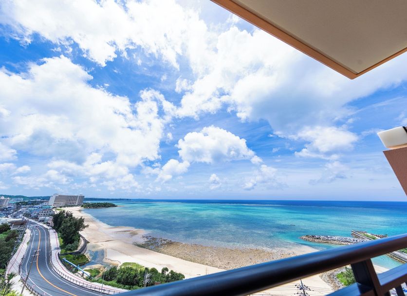 Kafuu Resort Fuchaku Condo Hotel in Onna with balcony view of beach, turquoise sea and cloudy sky