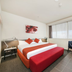 Abode Woden Canberra room with king bed, red bench, chair and large windows with city view