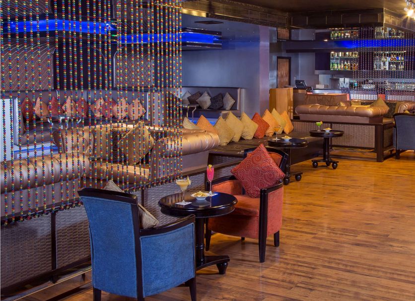 Radisson Blu Kochi lounge with colorful seating, wooden floor, and bar area in Kochi