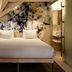 Kruisherenhotel Maastricht guest room with bed, floral mural wall and open bathroom doorway
