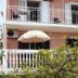 Apartments Alissa in Hvar, pink facade with balconies, white shutters, and garden umbrellas