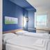 B&b Hotel Erlangen-tennenlohe room with twin beds, blue accent wall, window and wall-mounted TV in Erlangen