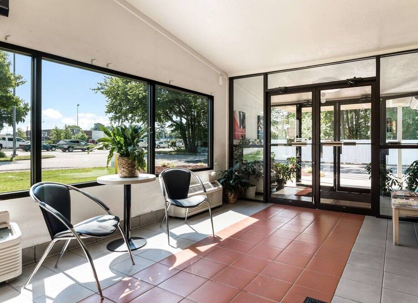 Motel 6 Newport News, VA lobby seating area with large windows and glass entrance doors