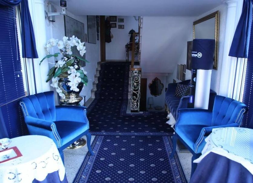 Hotel Irmchen in Maintal lobby with blue chairs, patterned carpet, floral arrangement and staircase