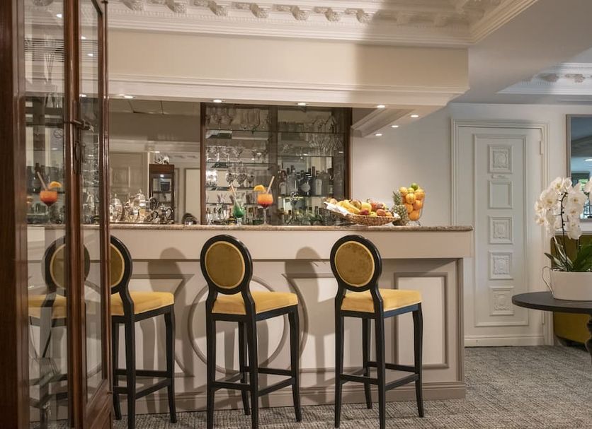 Hôtel Petit Palais bar area in Nice with high stools, mirrored shelving and floral arrangements