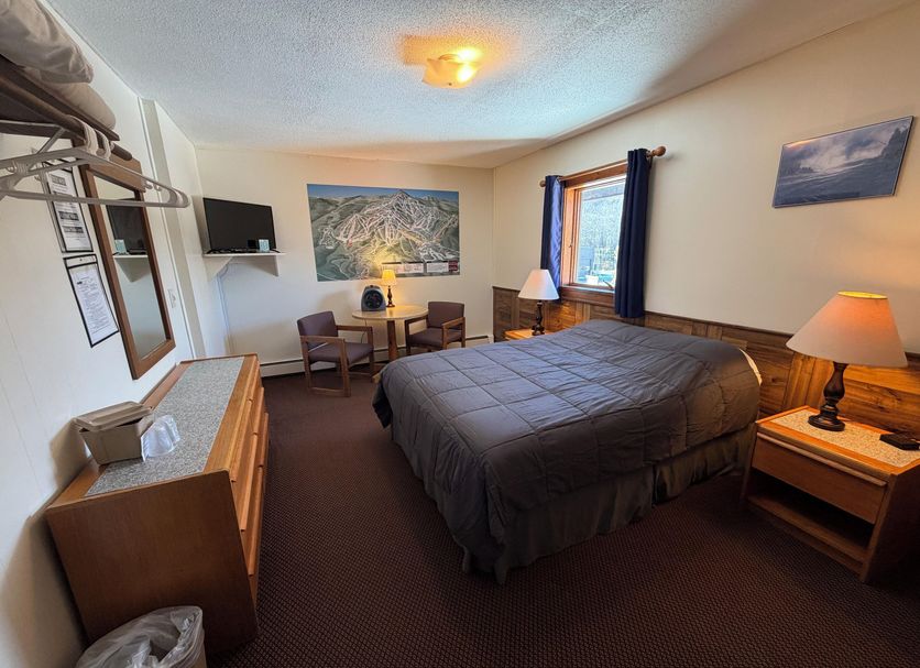 Mountain Sports Inn in Killington guest room with king bed, mountain artwork, and TV
