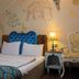 Elif Hatun Konagi in Tarsus, room with blue tufted headboard, bedside lamp, and painted wall art