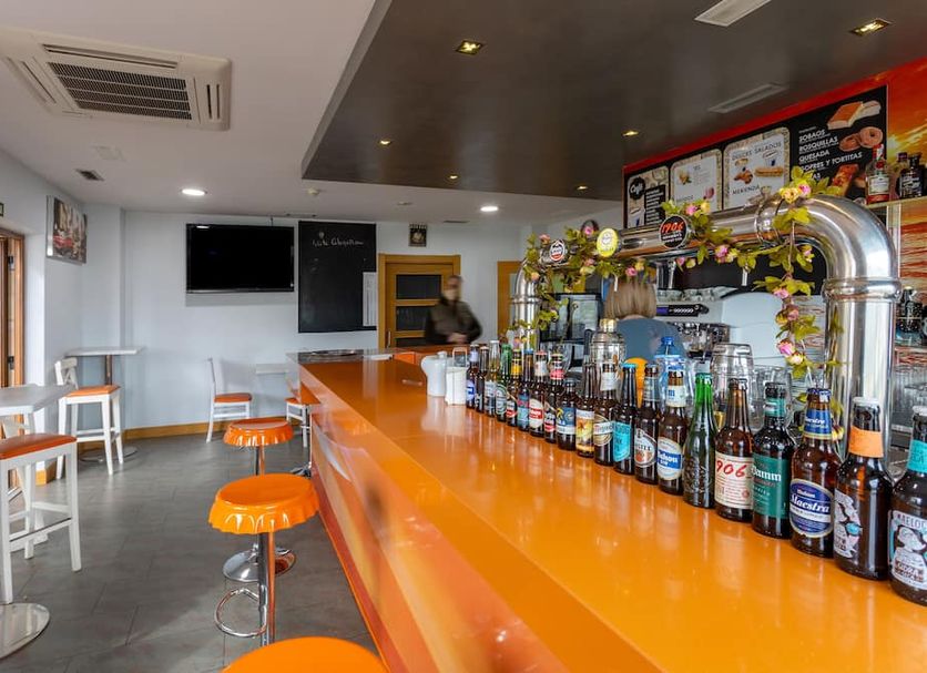 Hotel Valle de Cabezón bar with orange counter, stools and drinks in Cabezón de la Sal