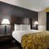 Baymont by Wyndham Branford/New Haven guest room with king bed, bedside lamps, and window air conditioner in Branford