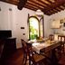 Le Rocche di Valiano kitchen and dining area with terracotta floor, wood beam ceiling, and garden doorway