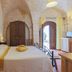 Masseria Casina Vitale room in Ceglie Messapica with stone-vaulted ceiling, wrought-iron bed and arched doorway.
