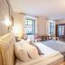 Safrano Palace in Braşov guest room with bed, chandelier, wardrobe, desk, and patterned wood floor