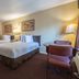 Hospitality Inn San Bernardino guest room with two beds, desk, chair, and lamps
