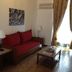 Gythion Hotel in Gytheio: red sofa, coffee table and lamp in a simple sitting area by a window.