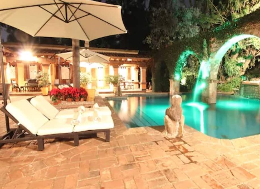 La Joyita Cuernavaca poolside terrace with lounge chairs, umbrella and illuminated pool at night