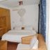 Kiriri Residence Hotel in Bujumbura room with bed, wicker chairs, and wood wardrobe