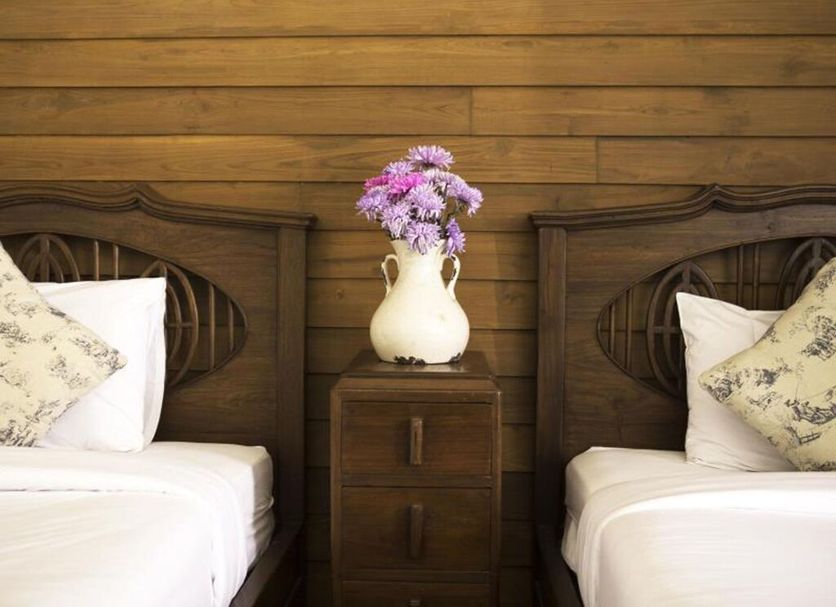 Baan Say-La Guesthouse in Chiang Mai, twin beds with floral pillows and vase of purple flowers