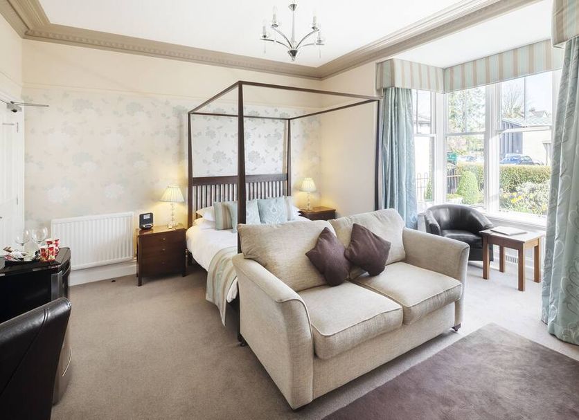 Hawksmoor Guest House in Windermere bedroom with four-poster bed, sofa, bay window and armchair