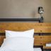 Hotelli Ville in Tampere: minimalist bed with wooden headboard, wall lamp and bedside shelf