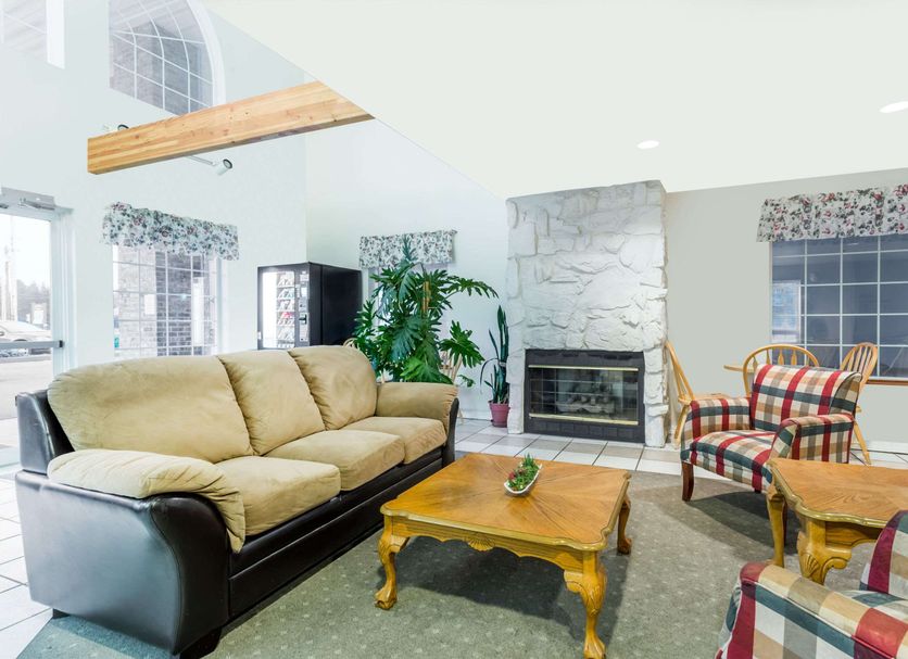 Days Inn by Wyndham Ocean Shores lobby with beige sofa, fireplace, coffee tables and plaid armchairs