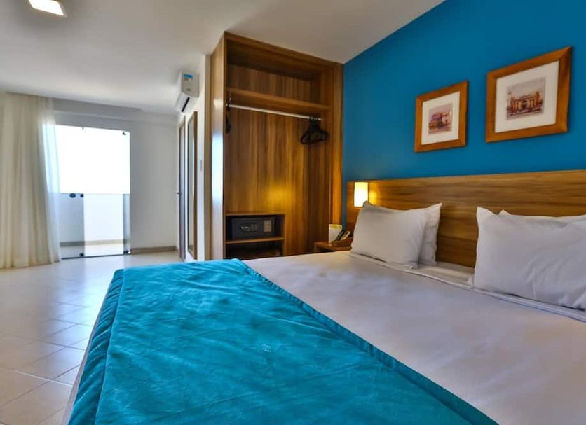 Arcus Hotel Aracaju by Atlantica guest room with king bed, blue accent wall and balcony door in Aracaju