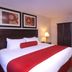 Century Casino & Hotel Edmonton guest room with king bed, red accents, lamp and wardrobe