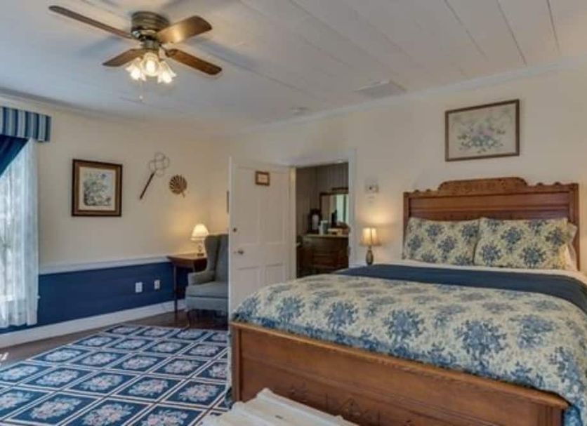 Carrier Houses Bed & Breakfast in Rutherfordton: floral canopy bed, armchair, and blue patterned carpet