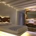 Eternal Suites in Mykonos bedroom with carved wood wall art, lit mirror vanity and low bed