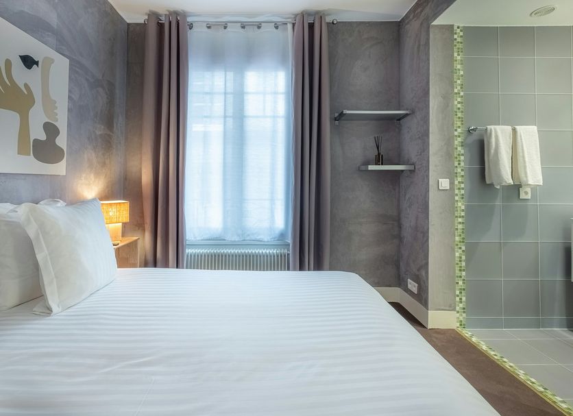 Makom Pereire in Paris guest room with bed, window, and tiled walk-in shower