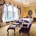 Crossbasket Castle, Glasgow: elegant bedroom with four-poster bed, chandelier, and large windows