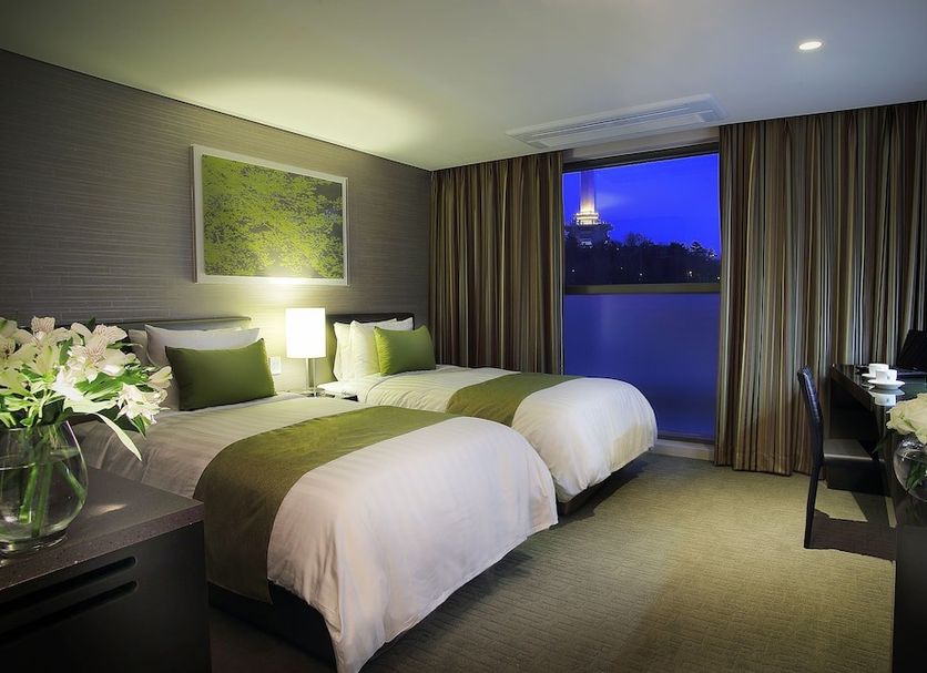 Aventree Hotel Busan guest room with two beds and a city view through the window
