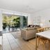 Metzo Noosa Resort living and dining area with sliding doors opening to a leafy patio in Noosa Heads