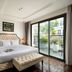 Anatole Hotel Hanoi guest room with tufted bed, bench, and balcony overlooking Hanoi greenery