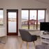Guesthouse Brekka in Husavik interior with dining table, chairs, TV, and large windows overlooking countryside