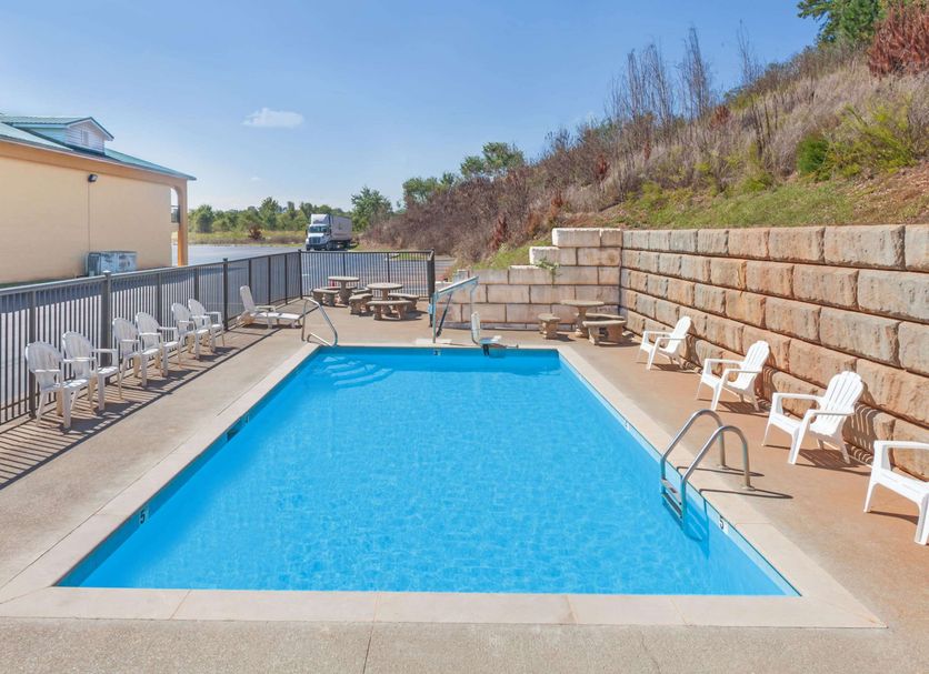 Days Inn by Wyndham Lenoir City outdoor pool with lounge chairs beside a hillside and patio seating