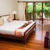 Riverhouse Resort in Mae Sariang room with wooden bed, balcony doors, and garden view