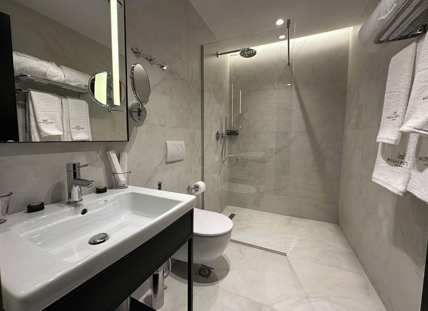 Mulaj Hotel in Tirana bathroom with walk-in shower, wall-mounted sink and toilet