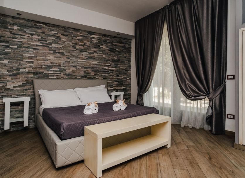Holiday Gli Archi, Fasano: modern hotel room with double bed, dark curtains and wood flooring