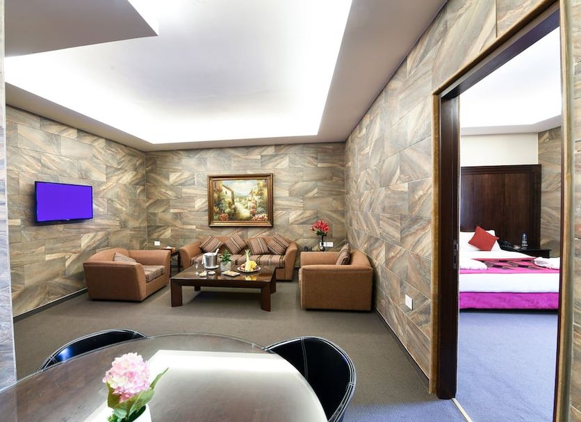 Reston Hotel in Jounieh lounge with leather seating, coffee table, wall TV, and bedroom doorway