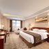 Grand Metropark Hotel Shangqiu guest room with king bed, desk and seating area in Shangqiu