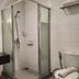 Hotel Glodok Plaza in Jakarta bathroom with glass shower, sink, mirror, and toilet