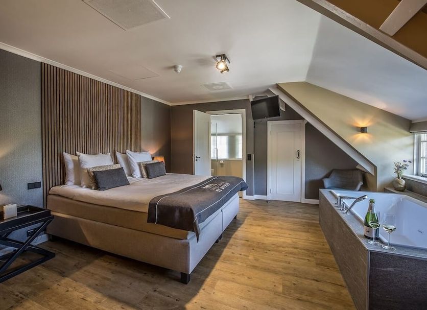 Landgoed De Uitkijk Hellendoorn room with king bed, sloped ceiling, and freestanding bathtub