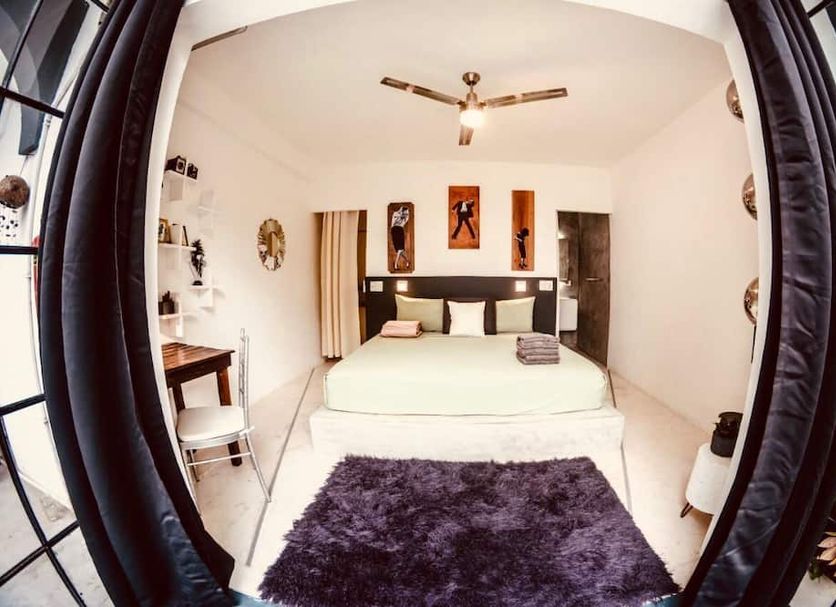 Radio Tulum guest room with bed, desk, ceiling fan and purple rug in Tulum