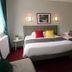 Hotel Le Canada in Hermanville-sur-Mer guest room with a double bed, single bed, and colorful pillows