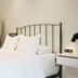 The Lakeside Prince Edward County bedroom with black metal bed, white bedding, fireplace, and bedside lamp.