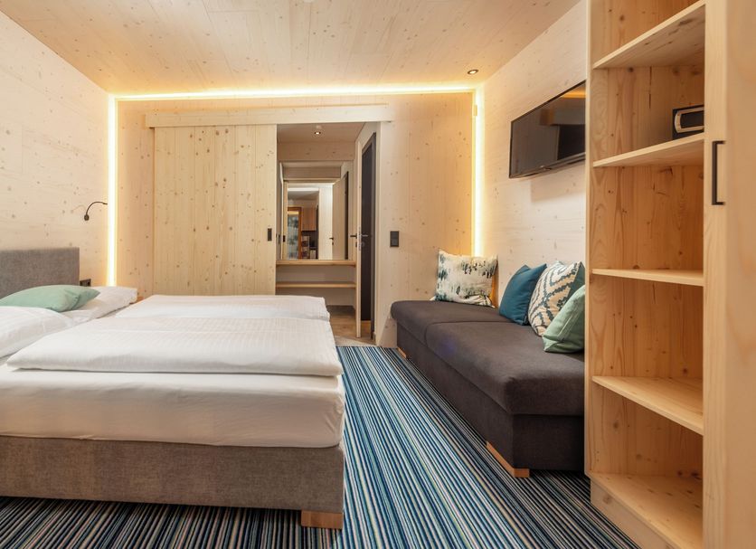 Ferienalm Panorama Apartments in Schladming: modern apartment bedroom with sofa and open shelving