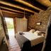 Refugio Del Pintor in Tilcara: rustic bedroom with stone wall, wood beams, and garden-facing doorway
